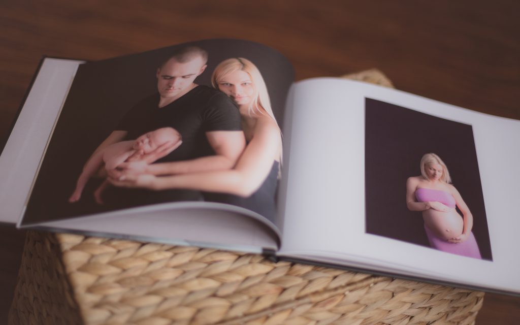 Atvērta fotogrāmata ar jaundzimušā ģimenes fotogrāfiju un grūtniecības fotogrāfiju